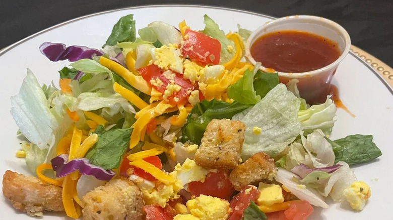 House salad from Texas Roadhouse on a white plate with dressing on the side
