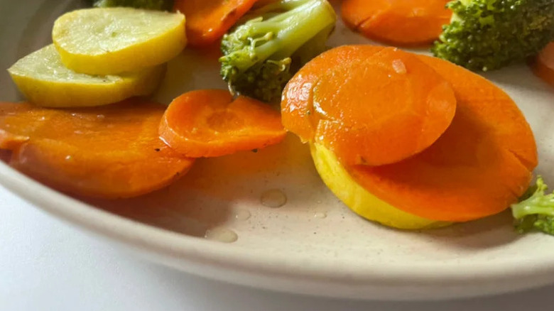 Steamed carrots, zucchini, and brocoli on a white plate
