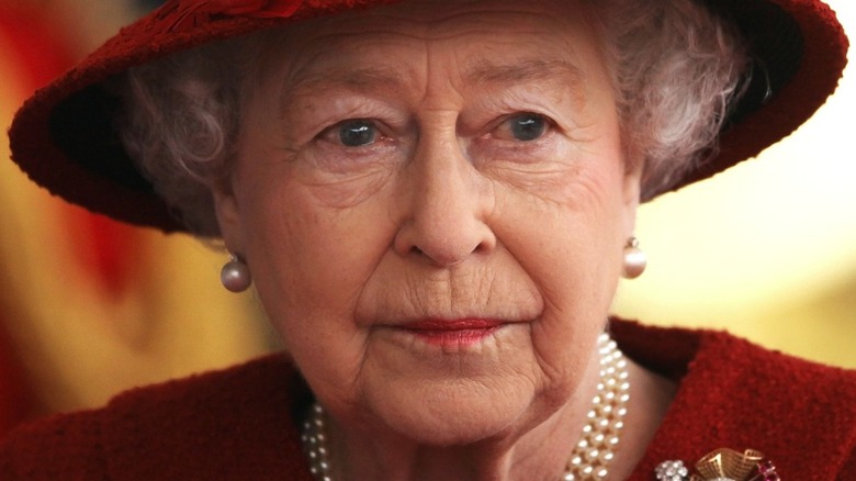 Queen Elizabeth II serious expression with red hat 