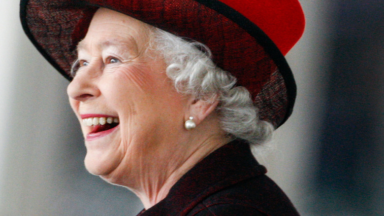 Queen Elizabeth II wearing red hat with wide smile