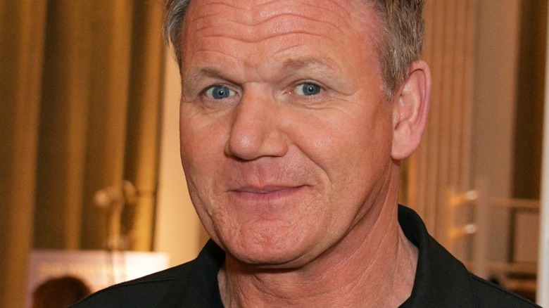 Gordon Ramsay with slight smile in front of gold background