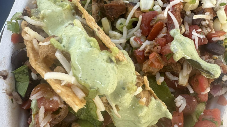 A close-up shot of a taco bowl from Chipotle topped with Cilantro Lime Sauce