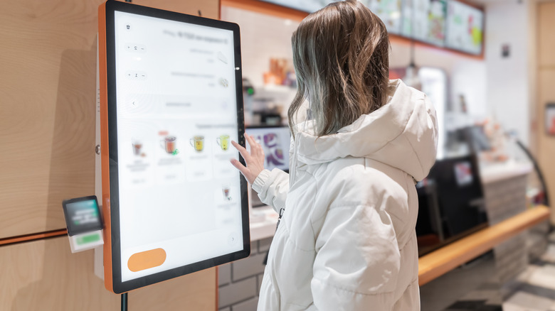 A customer ordering on a touch screen in a fast food restaurant