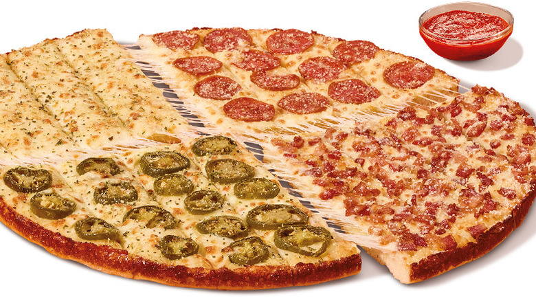 Little Caesars Four-N-One Stix beside a cup of dipping sauce isolated on a white background
