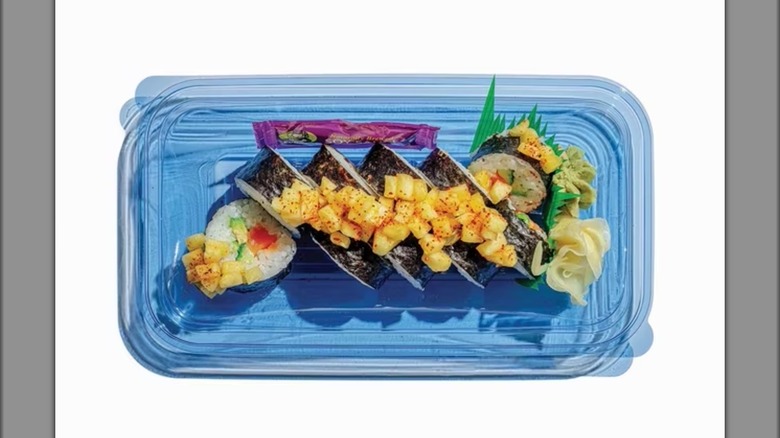 Blue plastic container with salmon and pineapple sushi.