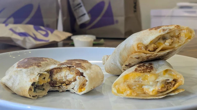 a bit taken out of a Taco Bell Crispy Chicken Crunchwrap Slider and Cantina Chicken Rolled Quesadilla on plate