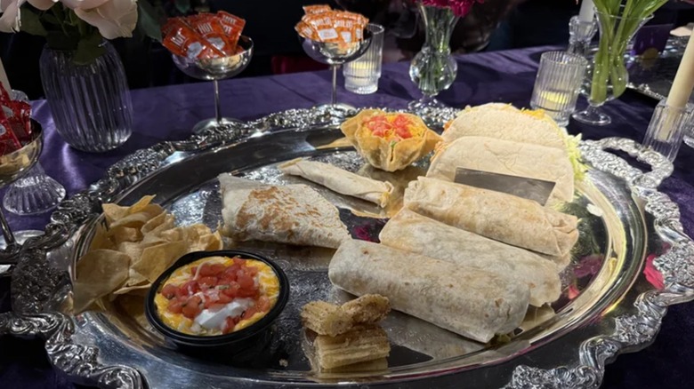 a platter of Taco Bell items like churros, burritos, taco salads, and tacos at the Taco Bell Luxe Value Menu event on fancy table setting