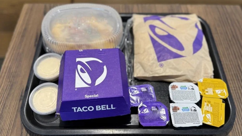 Tray from Taco Bell with diablo nuggets, crunchwrap, and fries in takeout packages with various sauces