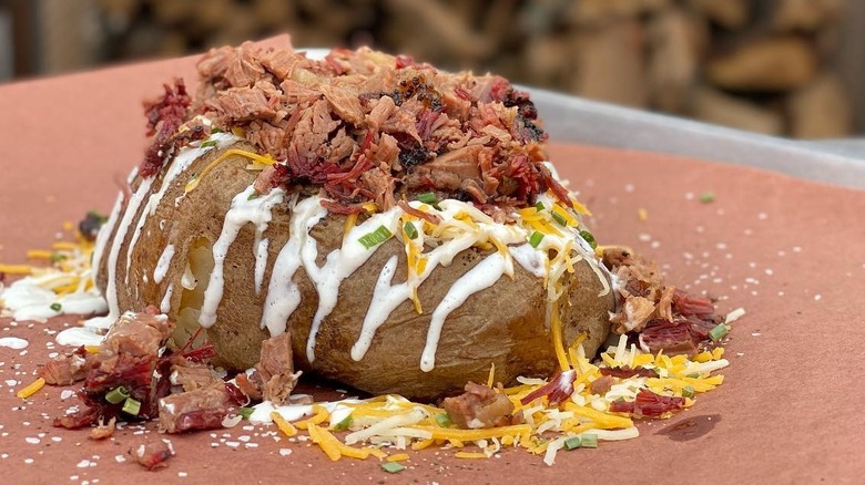 a baked potato stuffed with shredded cheese, sour cream, and brisket