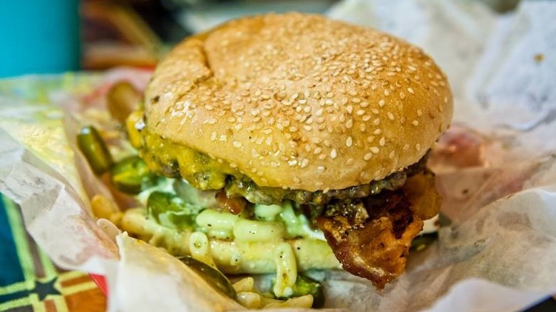 a bacon cheeseburger on a sesame seed bun in hamburger wrapper