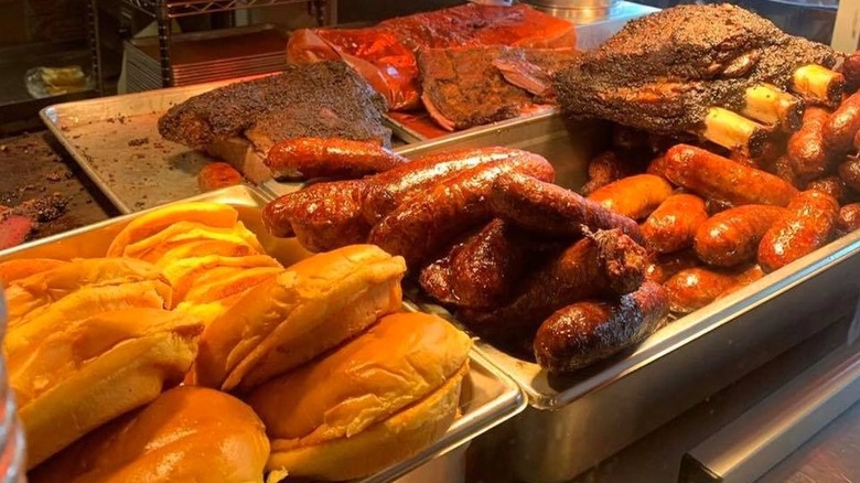 metal banquet trays of brisket, sausages, and buns in restaurant kitchen
