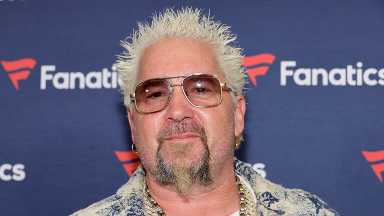 Close up of Guy Fieri posing wearing transparent sunglasses