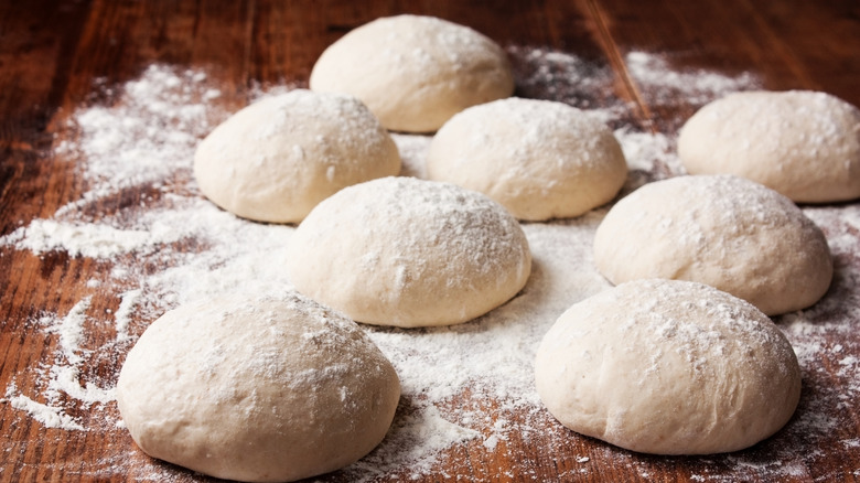 Balls of pizza dough on a floured counter