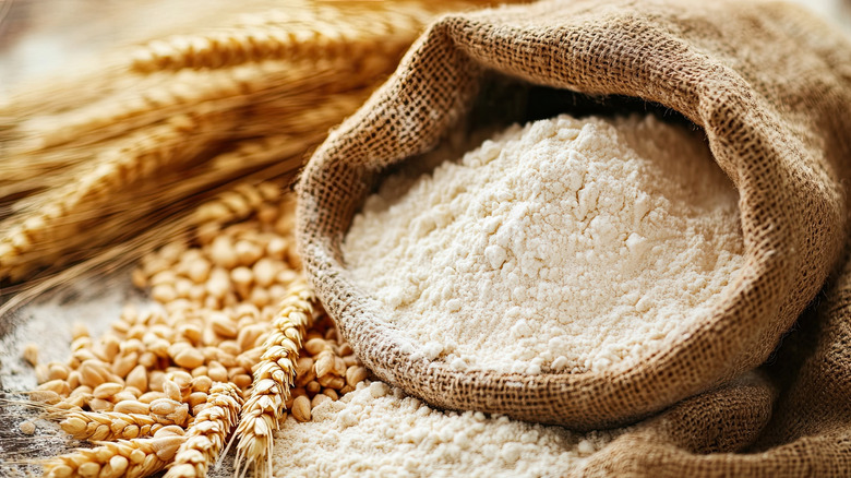 A sack of flour next to ears of wheat