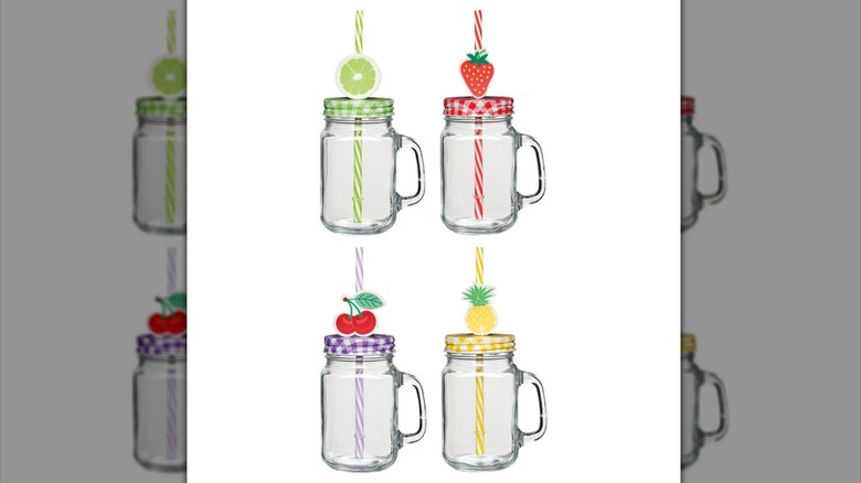 Four drinking jars with lids and straws decorated with fruit.