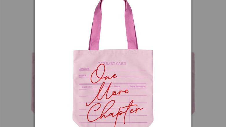 Pink library card tote bag with the phrase "One more chaper" printed in red