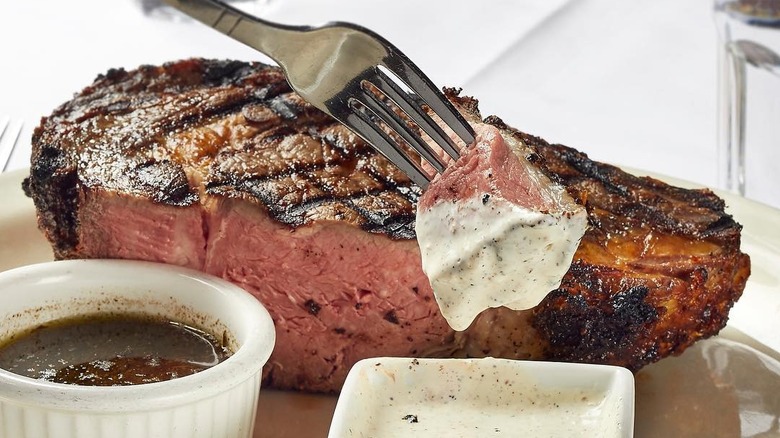 Prime rib served alongside au jus and a creamy horseradish sauce at St. Elmo Steak House