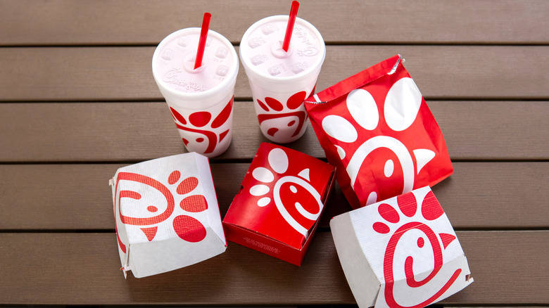 Chick-fil-A takeout boxes and cups sit on a wooden table.