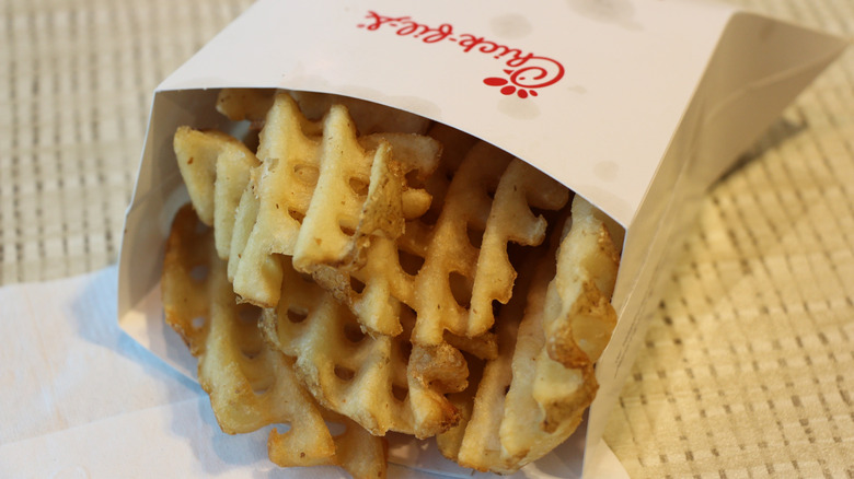 A box of Chick-fil-A waffle fries is tipped out onto a table.