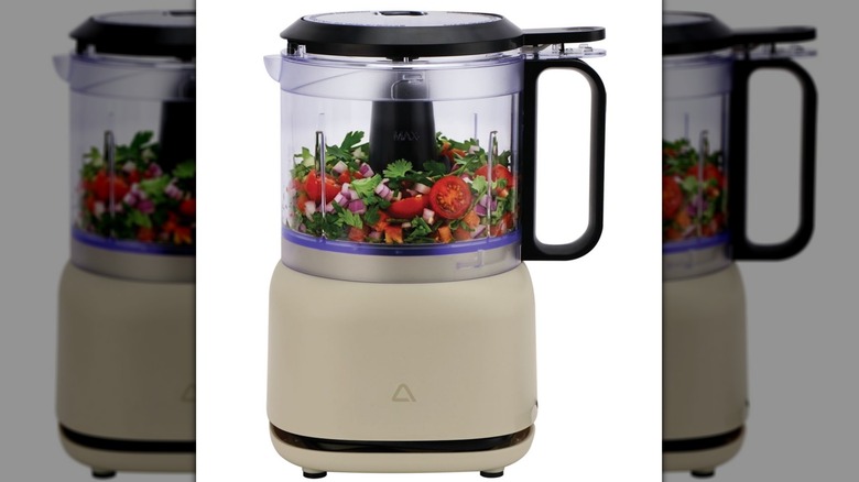 A mini food processor or chopper with chopped vegetables inside.