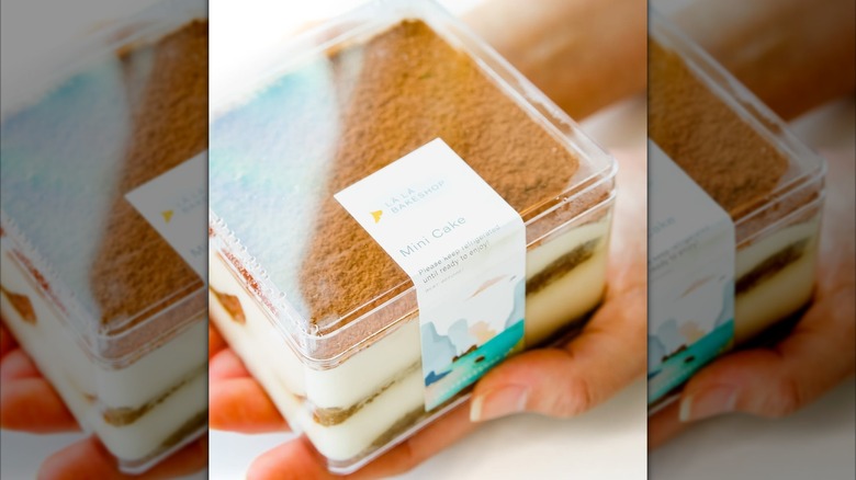 A small layered cake packaged to-go in a clear plastic box