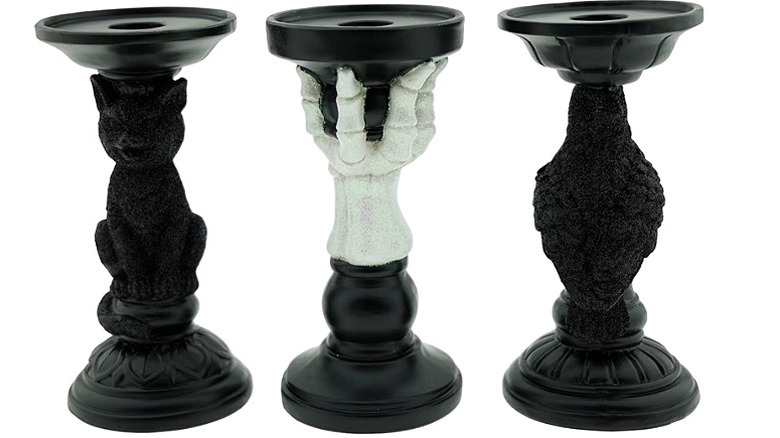 Halloween-themed black candle holders with a skeleton hand, raven, and a cat