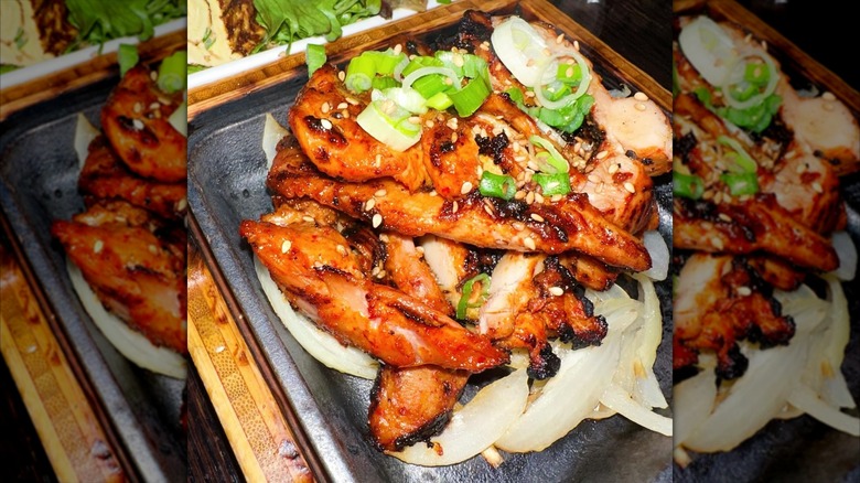 a Korean style meat dish with stir-fry strips of chicken, sesame seeds, and green onion