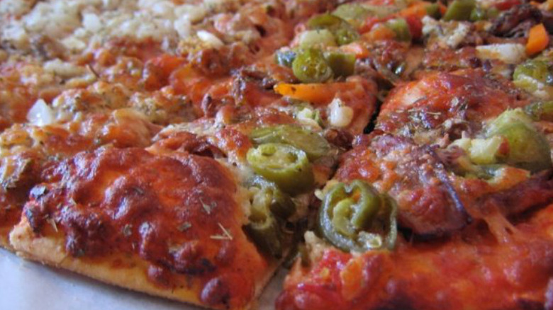 a thin crust pizza with peppers and other toppings