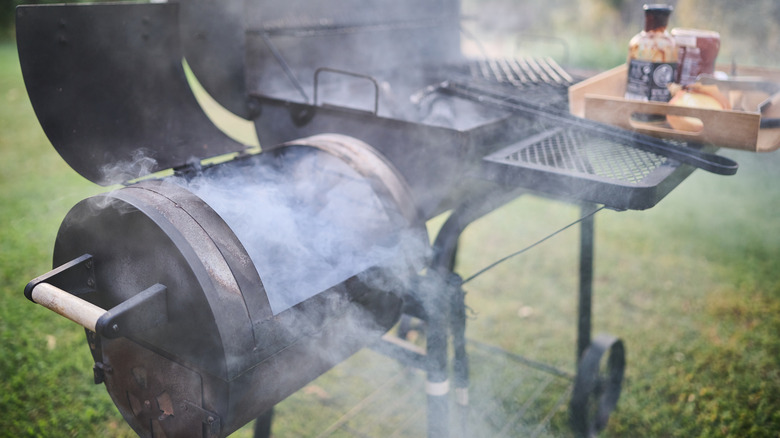 Metal meat smoker attached to a backyard barbecue grill