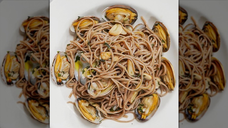 Whole wheat linguini pasta dish tossed with clams, garlic, and olive oil in soup plate