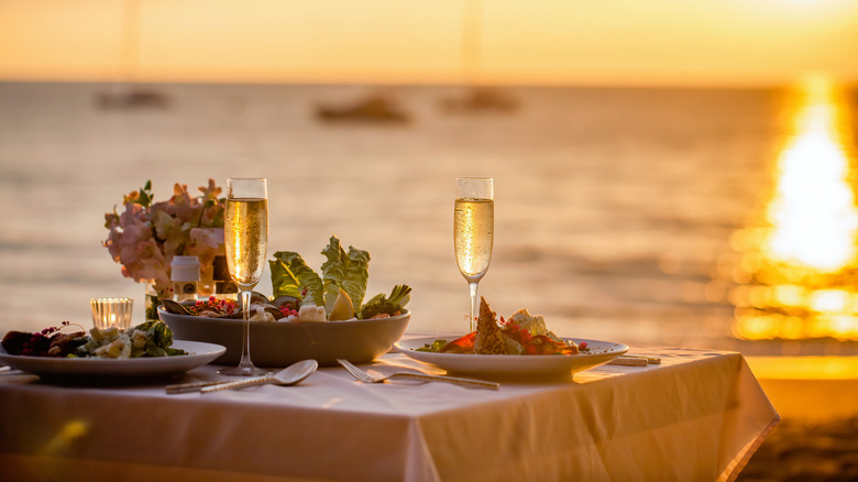 Beachside table prepared for a fancy romantic dinner for two at sunset