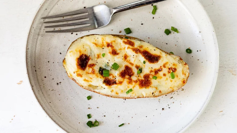 twice baked potato on a white plate with a fork