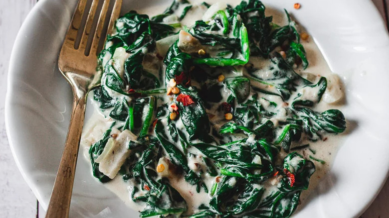 White bowl of creamed spinach with fork