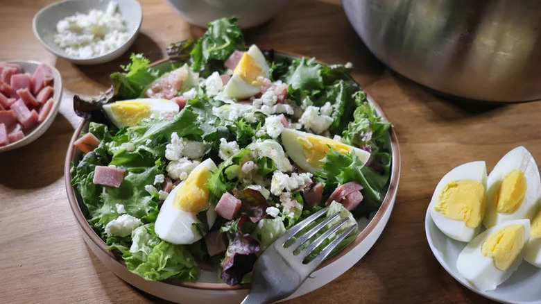French bistro salad in a bowl with a fork and eggs off to the side