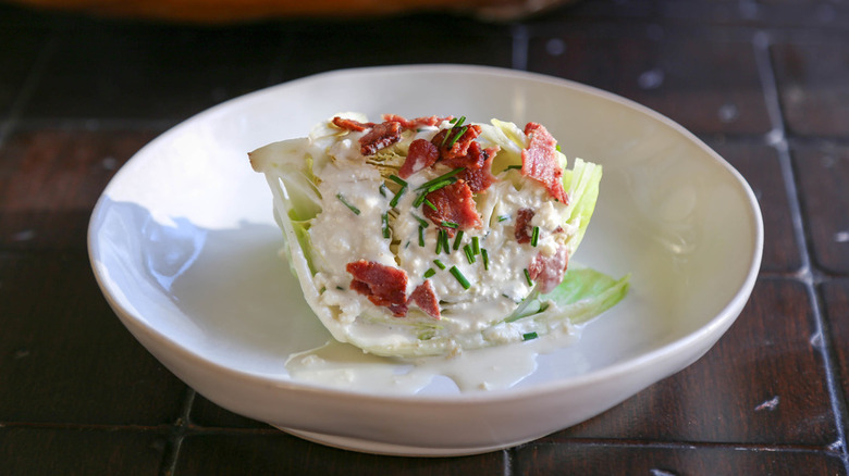 Wedge salad with bacon and dressing in a white bowl