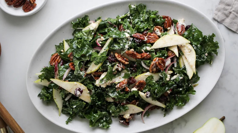 Kale Salad With Pears And Maple Pecans on a white plate