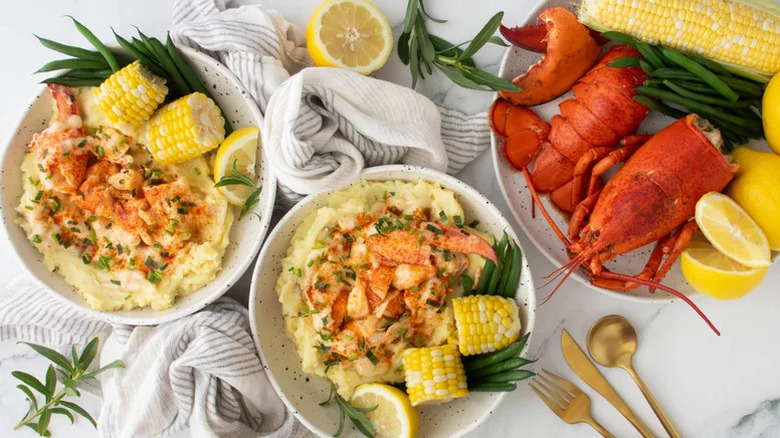 two bowls of lobster mashed potatoes with lobster and corn garnishes