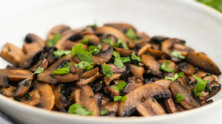 Close up of sauteed mushrooms in a white bowl