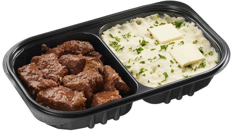 Pre-cooked meal of braised beef and mashed potatoes in a plastic tray.