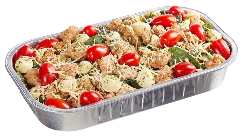 Pre-made pasta dish with sausage and vegetables in tray.