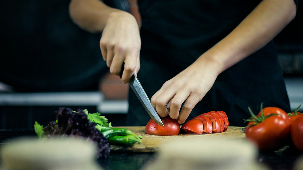 Hands cutting tomato with bearclaw grip