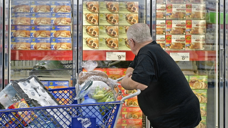 Person with shopping cart looking at items in Sam's Club freezer.