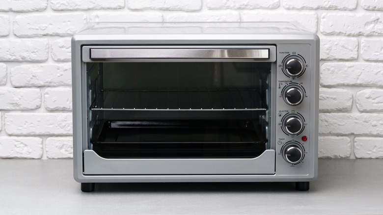 Metal toaster oven against a white brick wall