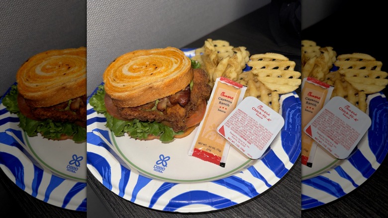 Chick fil A Avocado Sriracha BLT on paper plate with cayenne ranch sauce packet and waffle fries