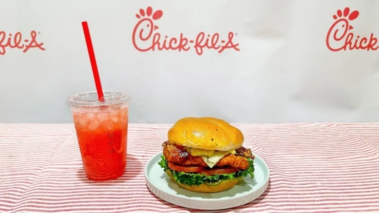 Chick-fil-A spicy Jalapeño Ranch Club Sandwich next to strawberry hibiscus drink in takeout cup on table