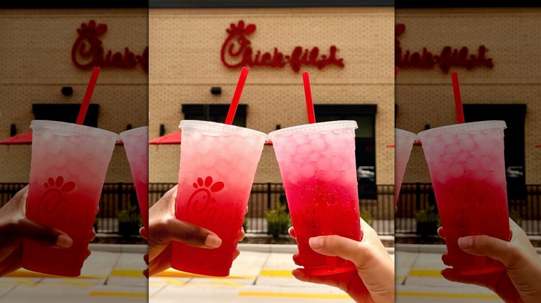 two people holding chick-fil-a Pineapple Dragonfruit Sprites in takeout cups in front of chick-fil-a building