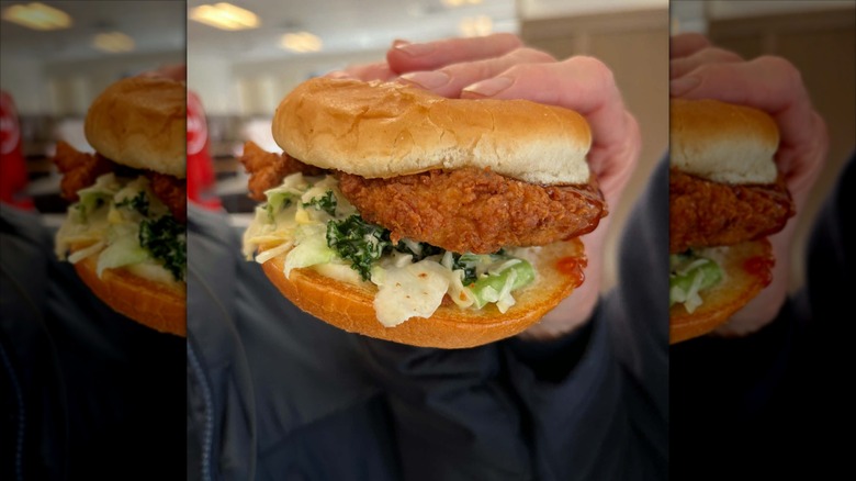 person holding a chick-fil-a sweet chili lime crunch sandwich