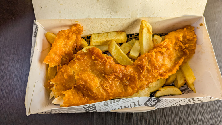 Fried fish on bed of fries in a box