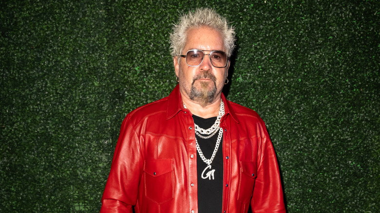 Guy Fieri with signature spiky hair in leather jacket, chain jewelry, and sunglasses