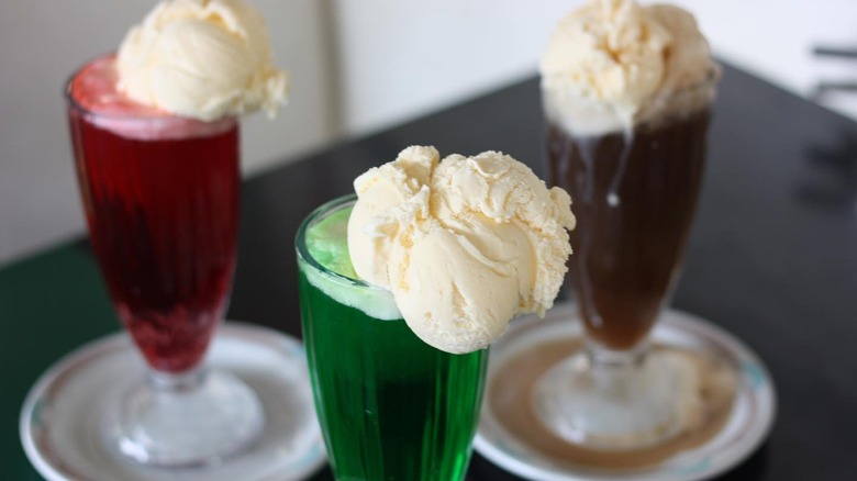 Three types of soda in vintage glasses each with a scoop of vanilla ice cream on top